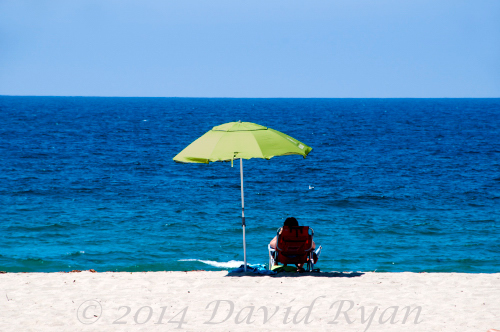Woman sitting under umbrella on beach