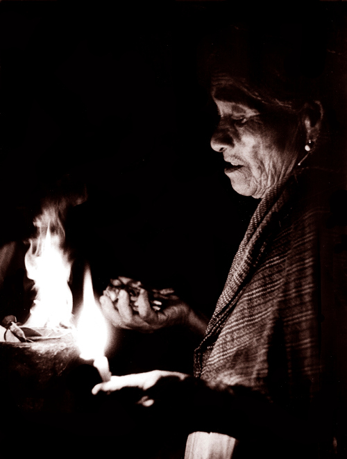  old mixteca curandera (shaman) blessing a handful of magic mushrooms by candle light